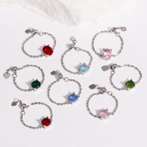 Close-up of adjustable chain rings with colorful gemstones and heart pendants