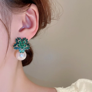 Macro view of floral emerald green crystal earrings with a large drop pearl detail