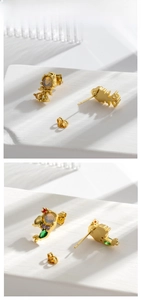 Macro shot of gold-plated fishtail earrings with colorful zircons and opal inlay