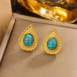 Macro shot of gold teardrop earring featuring blue textured stone and sunburst border