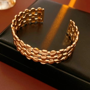 Detailed macro view of a gold triple-layer hollow dot cuff bracelet on black display