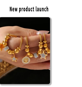 Detail of gold snake chain bracelet with tree of life and star pendants held by hand