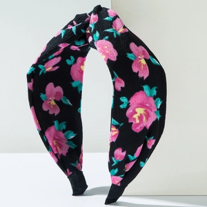 Détail d'un serre-tête croisé à motifs floraux roses sur tissu noir élégant