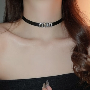 Gros plan détaillé d'un collier choker en similicuir noir avec lettres miu en strass