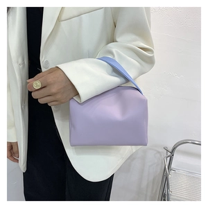 Detail view of purple PU leather handbag held by a model wearing a white suit blazer