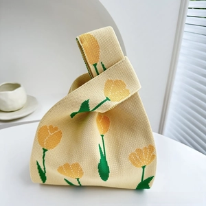 Detail of knitted beige tote bag featuring yellow tulip patterns and soft green stems