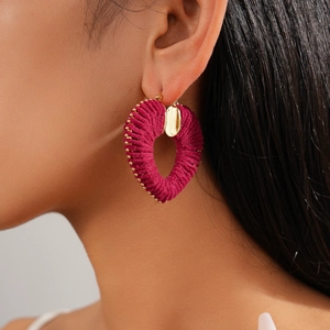 Detail of burgundy knitted heart hoop earring with gold beads and heart pendant