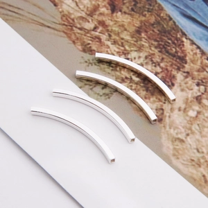 Macro view of four polished silver S925 curved tube beads for DIY jewelry making