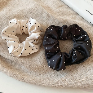 Detail of silk-like polka dot scrunchies set in black and white on textured linen fabric