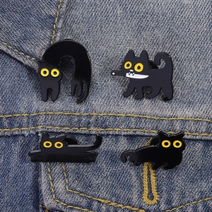 Detailed view of four black cat enamel pins pinned on blue denim fabric texture