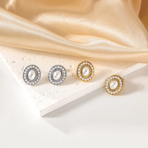 Elegant gold and silver oval stud earrings with pearls on silk and stone background