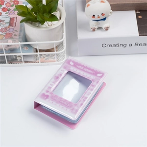Pink 3-inch mini photo album with cloud cover and heart-shaped window on a desk