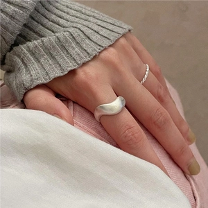 Close-up of minimalist wave textured silver ring and twisted band on hand