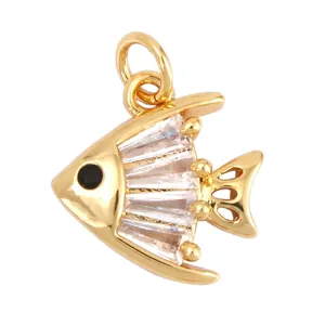 Détail d'un pendentif poisson en laiton doré avec zircons baguette et œil noir brillant