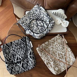 Detailed embroidery of floral and bird patterns on flat canvas crossbody bags with leather straps