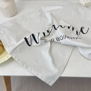 Close-up of white cotton linen napkins with Welcome and A New Beginning script print