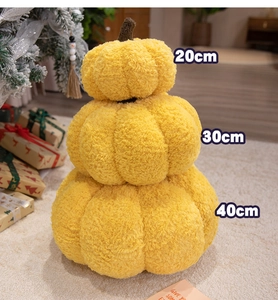 Three sizes of yellow plush pumpkin pillows stacked in a cozy festive holiday setting