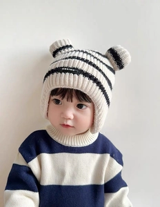 Detail showing the knitted texture and 3D animal ears on the beige striped baby hat