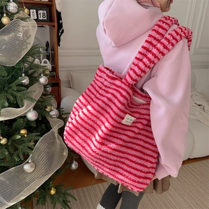 Soft pink striped plush tote bag with sparkle heart tag shown in a warm cozy setting