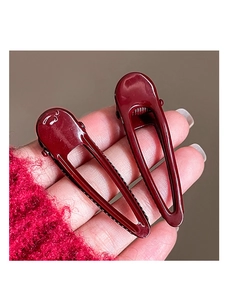 Close-up of two deep wine red geometric drop-shaped metal hair clips with glossy finish