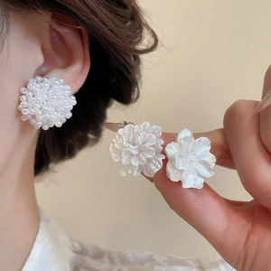 Dettaglio orecchini a lobo a fiore bianco con perle e petali dalla trama strutturata