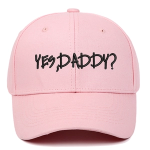Pink baseball cap with black YES DADDY embroidery and curved brim in plain white background