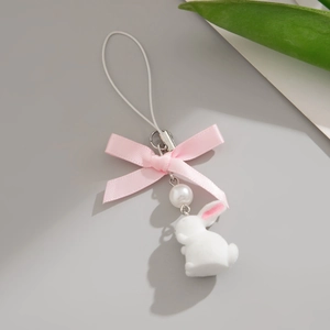 Detail of plush white rabbit phone charm with pink ribbon bow and pearl bead accent