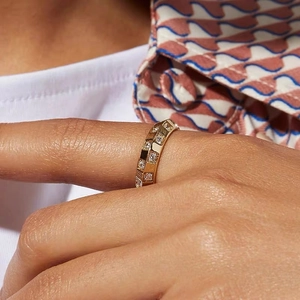 Close-up of a rose gold diamond-encrusted ring with a plaid pattern on a model hand