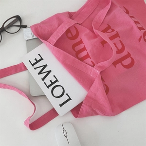 Nahaufnahme der pfirsichrosa Canvas-Tasche mit strapazierfähiger Textur und rotem Schriftzug