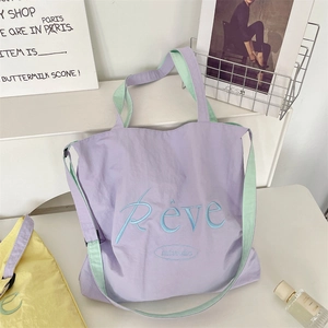 Detail of Rêve embroidery on purple and mint green canvas tote bag in a lifestyle setting