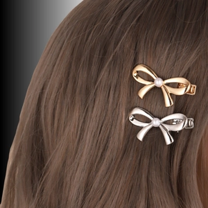 Close-up of gold and silver metal bow hair clips with pearls on brunette hair