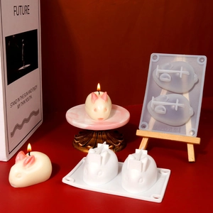 Macro shot of 2-cavity silicone bunny mold with finished rabbit candles on red background