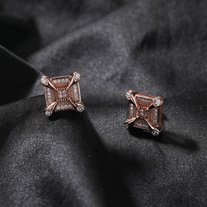 Detailed macro view of rose gold square stud earrings with zircon inlay on dark silk