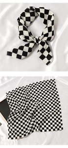 Détail d'un foulard en soie à damier noir et blanc sur fond de satin élégant et lisse