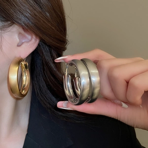 Detail of chunky gold and silver brushed metal hoop earrings with matte finish texture