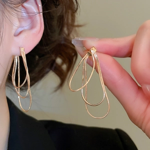 Détail de boucles d'oreilles en chaîne serpent dorée montrant le drapé et la texture