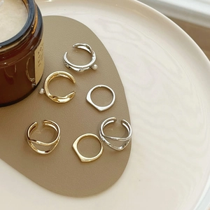 Detailed close-up of six geometric metal rings with pearl accents in gold and silver finishes