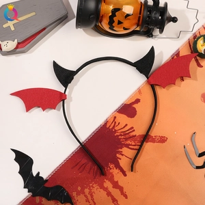 Top view of a black devil headband with red bat wings on a Halloween themed background