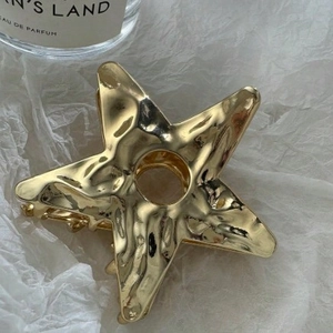 Golden hollow star metal hair claw clip with hammer texture on a white background