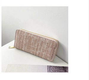 Detail of long beige striped wallet with gold zipper and woven textured fabric