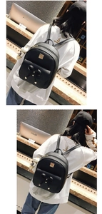 Detail of black PU leather backpack with a large bow, gold studs and white bear charm