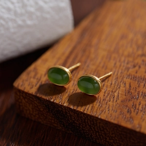 Close-up of oval green jasper sterling silver stud earrings on dark wood surface