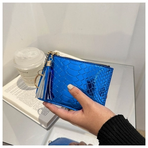 Close-up of blue crocodile texture mini clutch bag with golden zipper and leather tassel