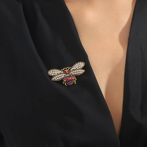Vintage golden bee brooch with pearls and enamel stripes worn on black clothing