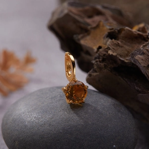 Macro view of a S925 silver gold-plated pendant with amber gemstone on a dark stone