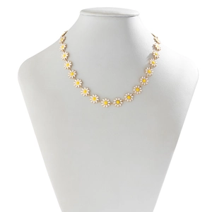 Bohemian gold daisy flower necklace with white enamel petals on jewelry display stand