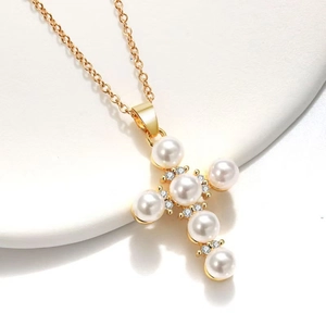 Macro detail of gold-plated cross pendant with white pearls and sparkling rhinestones