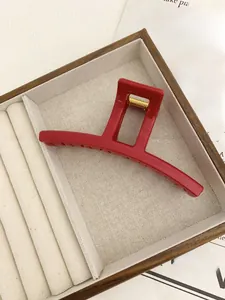 Detailed view of a large glossy red curved hair claw clip with golden metal spring