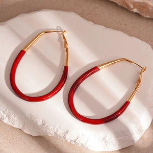 Detail of large oval red enamel drop earrings on a textured stone display