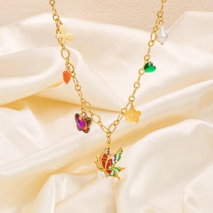 Detail of gold necklace with colorful butterfly, flower and heart charms on silk fabric